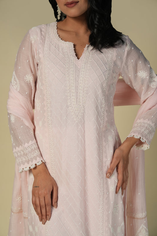 A close-up image of a woman wearing a baby pink mul suit set with chikankari detailing.