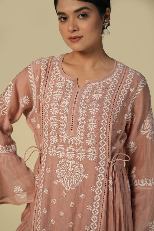 A woman wearing a dusty rose kurti set with intricate white embroidery.