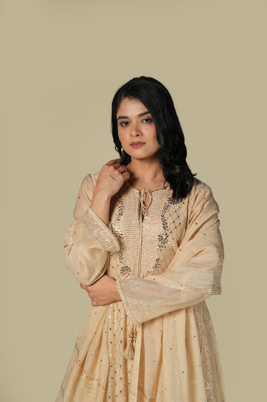 A woman wearing an ecru-colored Mukaish Mul Chanderi suit set with delicate embroidery and a dupatta.