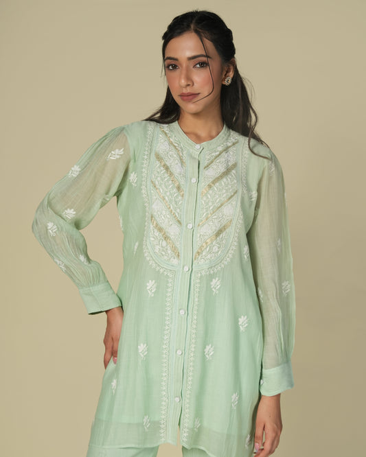 A woman wearing a green mul co-ord set with chikankari work, posing for the camera.