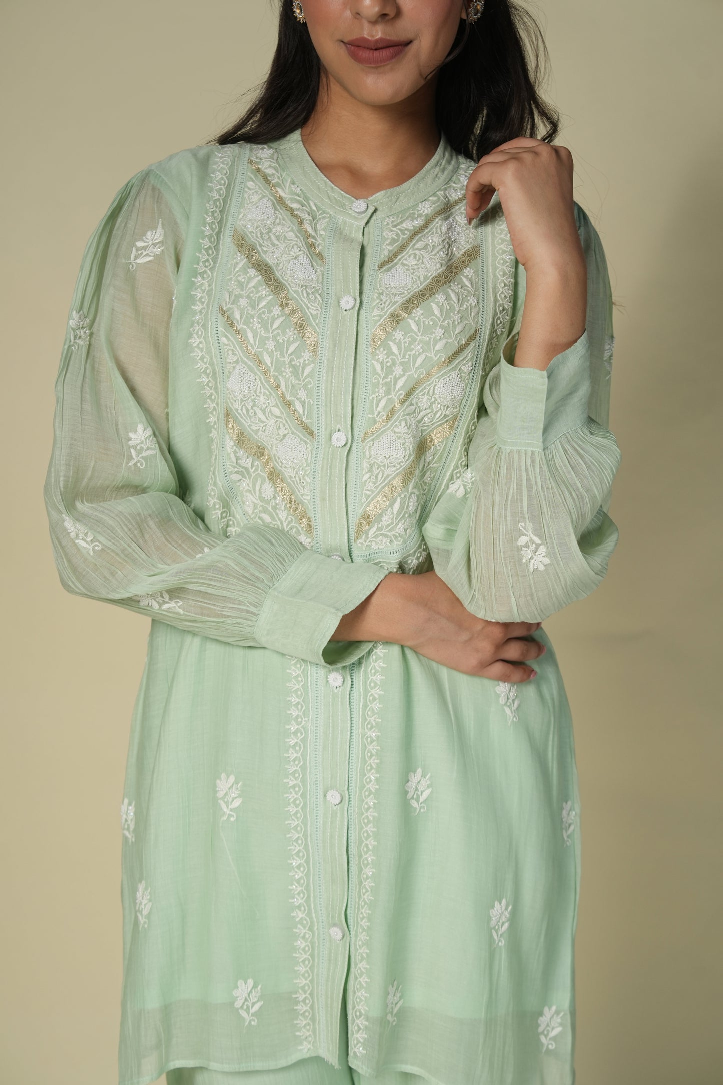 A woman wearing a green mul co-ord set with chikankari work, posing for the camera.