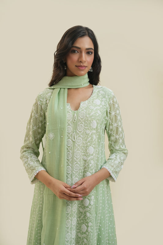 A woman wearing a green anarkali with floral chikankari patterns and a dupatta.