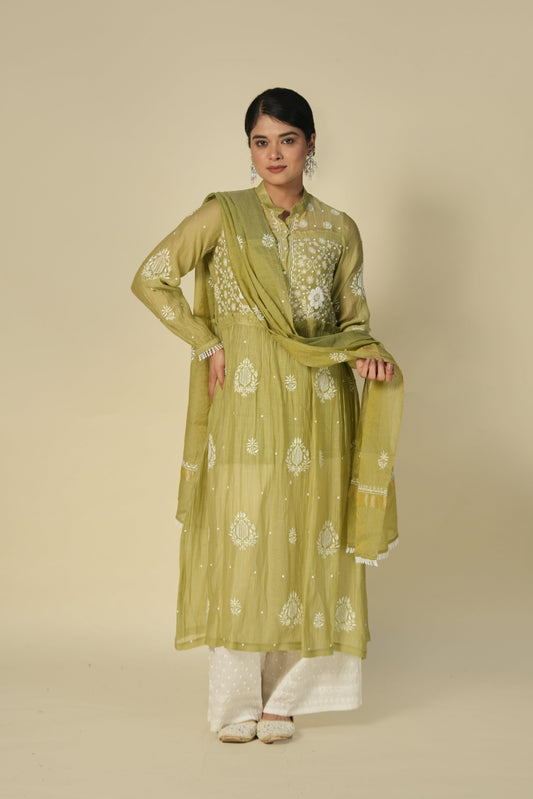 A woman wearing a green A-line suit set with chikankari embroidery, consisting of a kurta, palazzos and dupatta.