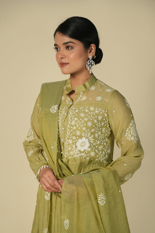 A woman wearing a green A-line suit set with chikankari embroidery, consisting of a kurta, palazzos and dupatta.