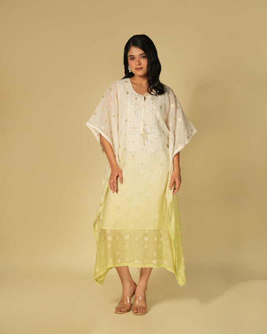 A woman standing in a studio setting, wearing a shaded lime green and white chikankari mul chanderi kaftan with golden zari details.