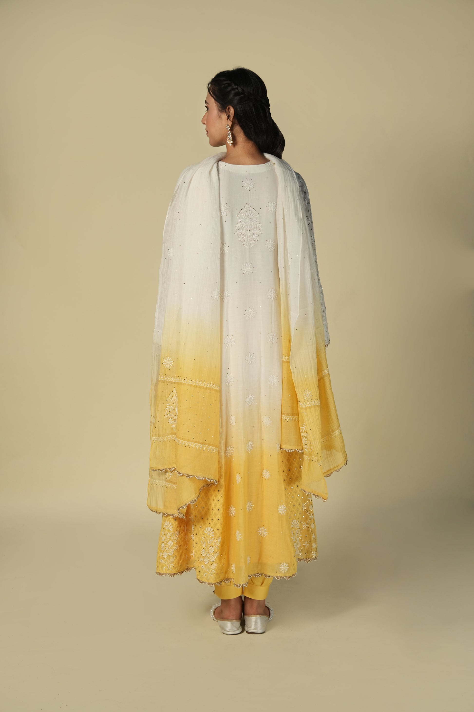 A woman wearing a yellow and white shaded chikankari jacquard cotton anarkali set with intricate embroidery.