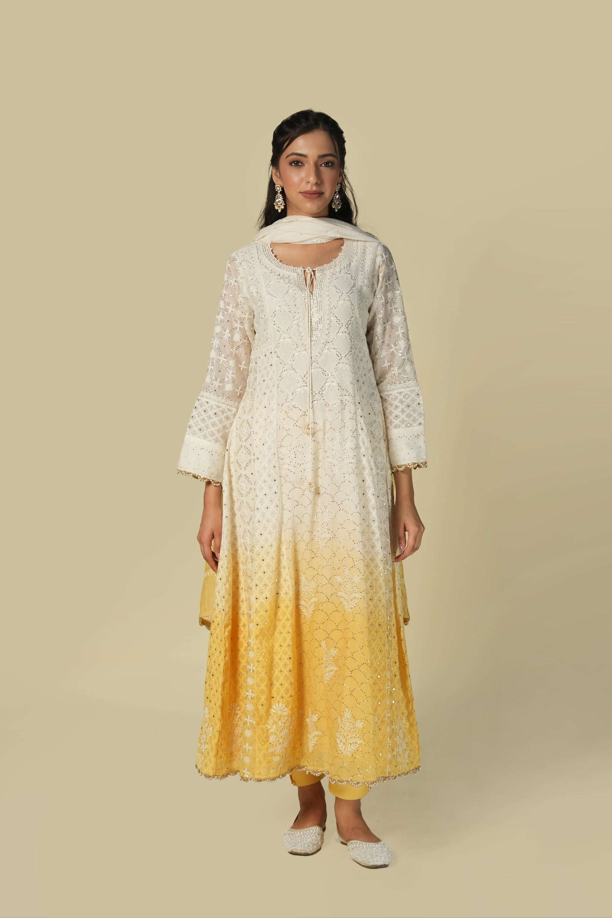 A woman wearing a yellow and white shaded chikankari jacquard cotton anarkali set with intricate embroidery.