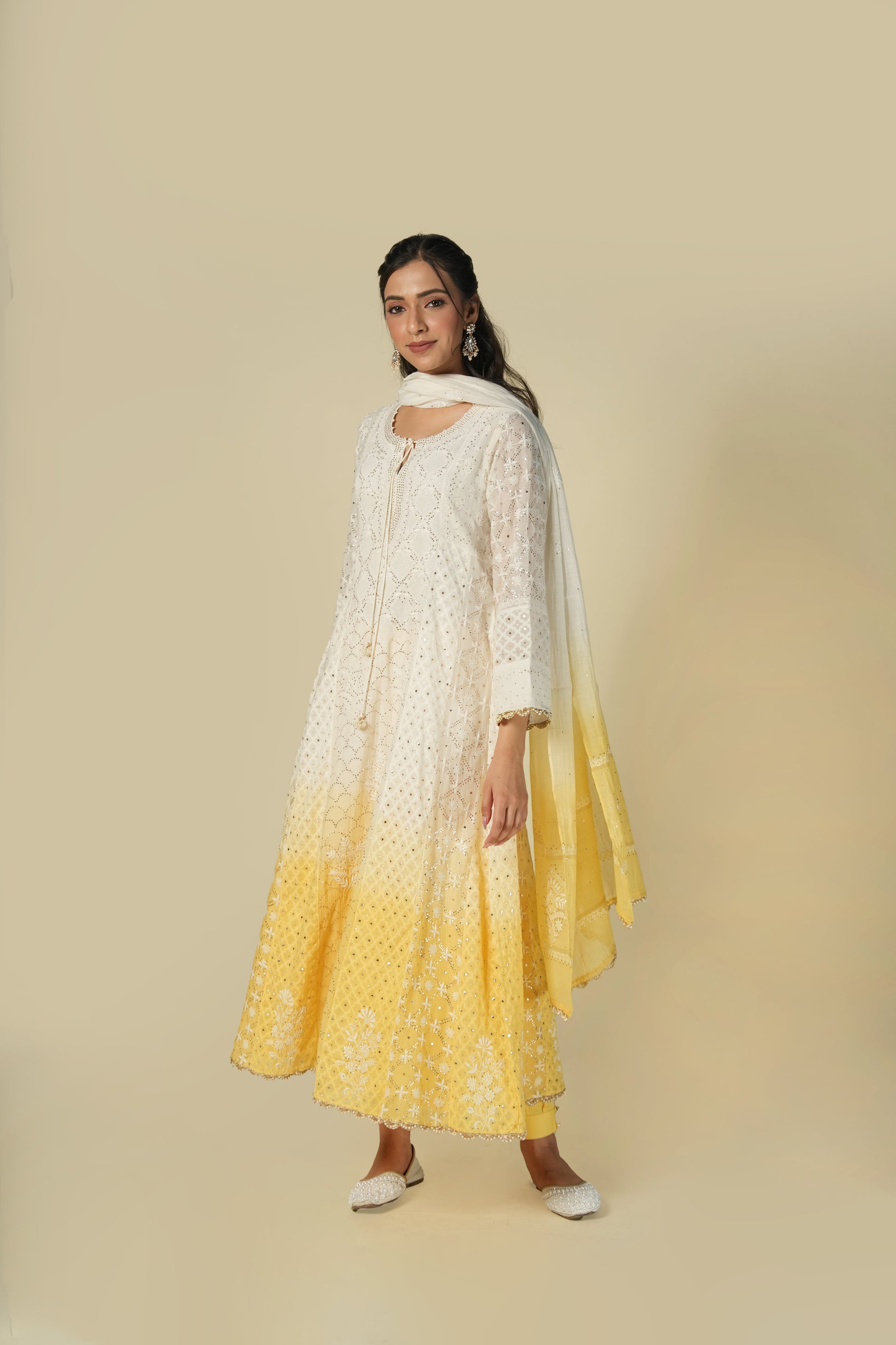 A woman wearing a yellow and white shaded chikankari jacquard cotton anarkali set with intricate embroidery.
