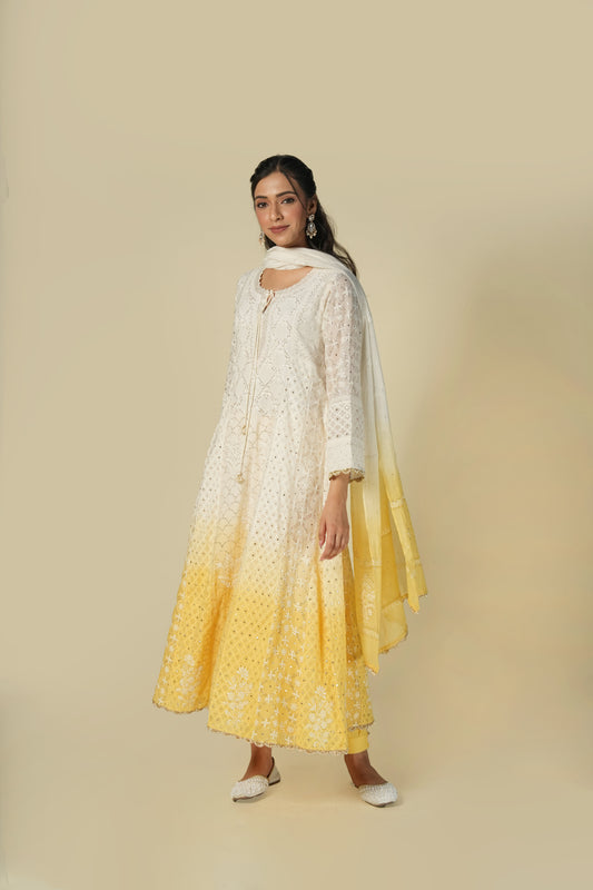 A woman wearing a yellow and white shaded chikankari jacquard cotton anarkali set with intricate embroidery.