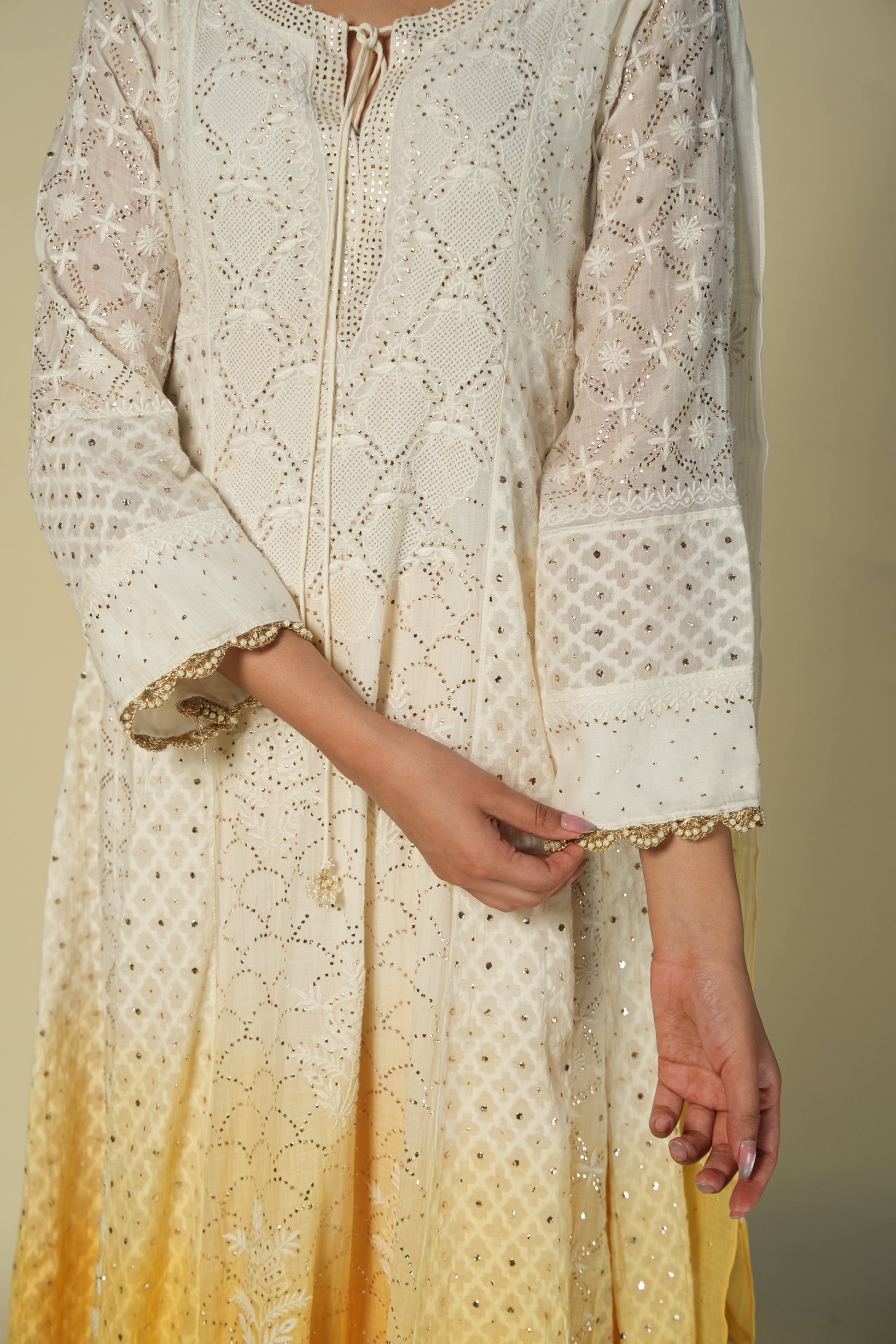 A woman wearing a yellow and white shaded chikankari jacquard cotton anarkali set with intricate embroidery.