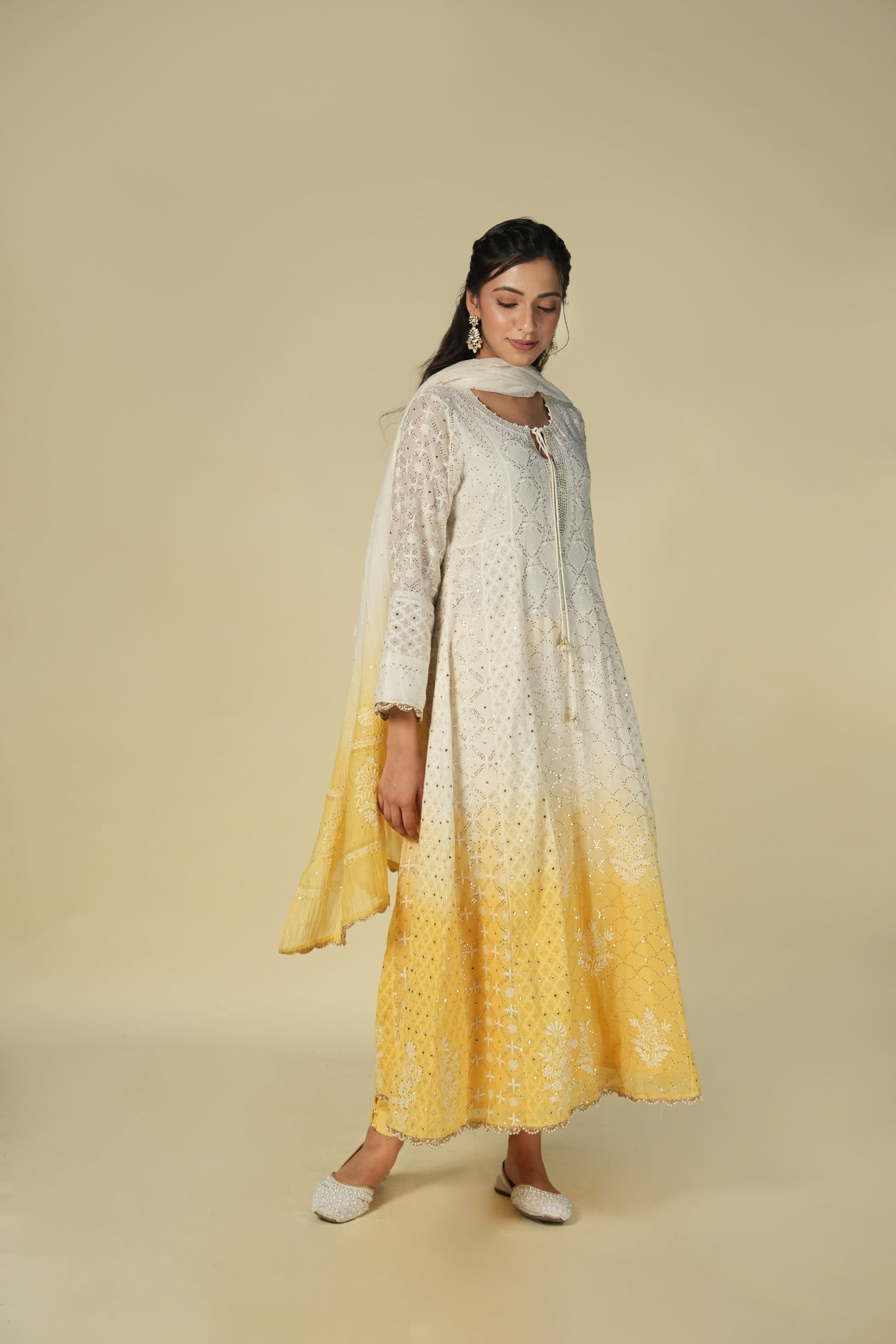 A woman wearing a yellow and white shaded chikankari jacquard cotton anarkali set with intricate embroidery.