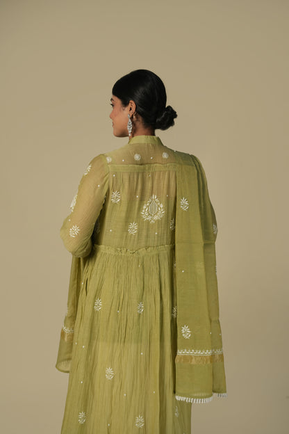A woman wearing a green A-line suit set with chikankari embroidery, consisting of a kurta, palazzos and dupatta.