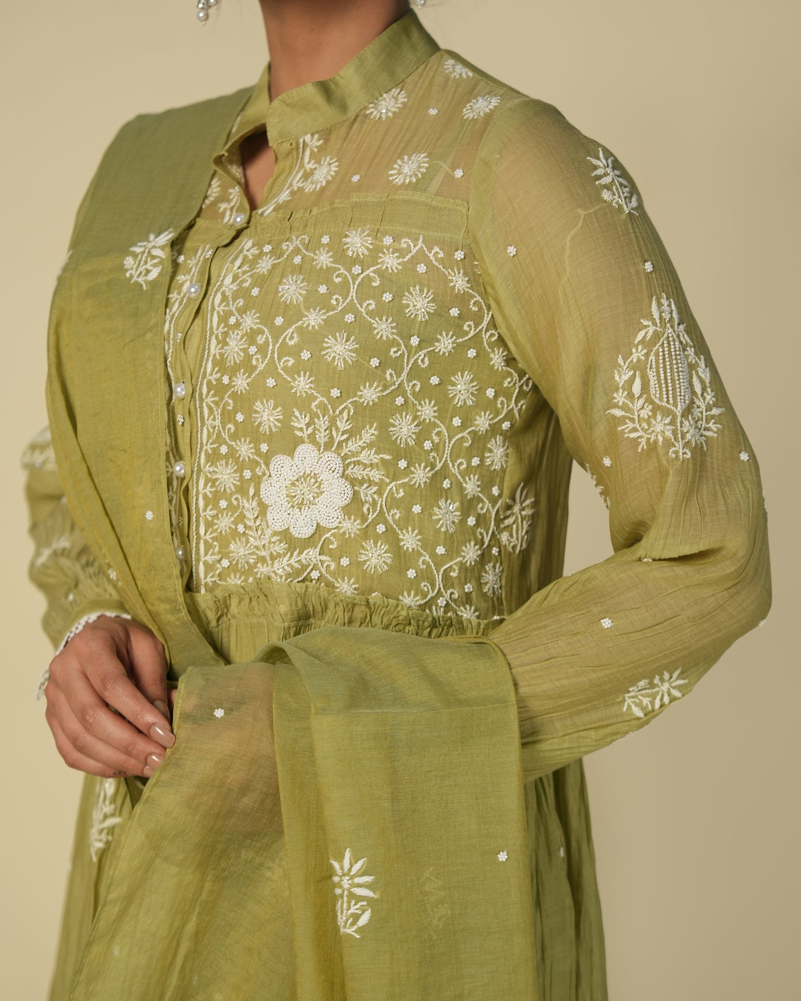 Green outfit with floral embroidery on a plain background